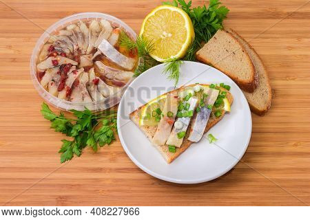 Open Sandwich Made Of Brown Bread, Slices Of Fillet Of Pickled Atlantic Herring, Fresh Lemon And Cho