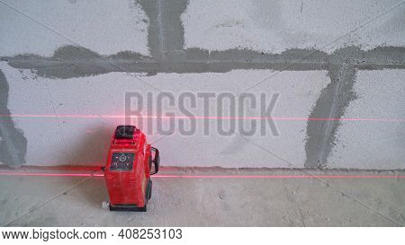 A Builder Makes Arrangements With A Laser Level At A Construction Site. Construction Laser Level And