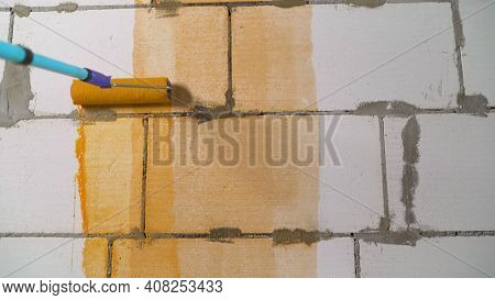 The Orange Wall Is Covered With Red Paint. Roller And Orange Wall. Paint Roller With Orange Paint. A