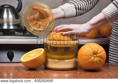 Female Hand Juicing Oranges. Closeup On Women's Hand Making Fresh Orange Juice. Squeezing Orange Jui