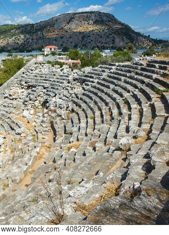 Rows of stone seats of ruins of Theatre in Letoon Ancient City in village Kumluova, Turkey. Sunny day, Greek culture ancient amphitheater architecture vertical photo