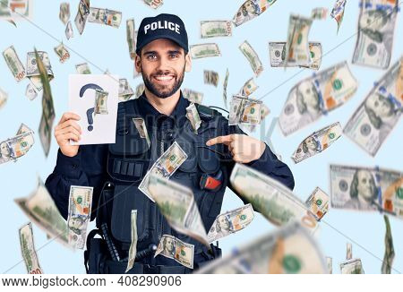 Young handsome man with beard wearing police uniform holding question mark pointing finger to one self smiling happy and proud
