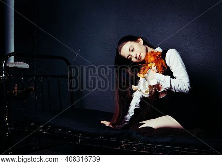 pretty girl with an old doll in an abandoned building