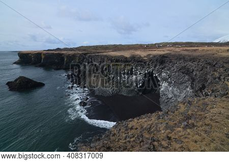 Tide Going Out On A Black Sand Beach With Basalt Columns.