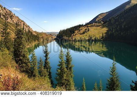 Alpine Kolsai Lake In Mountain Gorge Surrounded By Trees On A Sunny Summer Day, Kazakhstan. Sunny Su