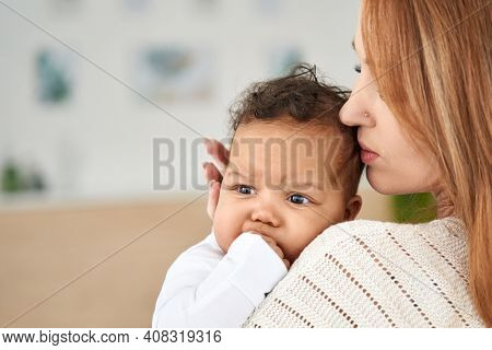 Loving Caucasian Young Mother Hugging Soothing Cute African American Infant Baby Girl Teething Bitin