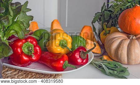 Sweet Peppers Paprika Of Red, Orange And Green Color, Fruits, Lettuce On A Plate On The Kitchen Tabl