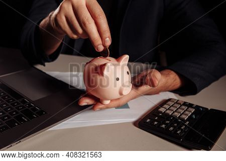 Man Putting Coin In Pink Piggy Bank. Savings And Investment Concept