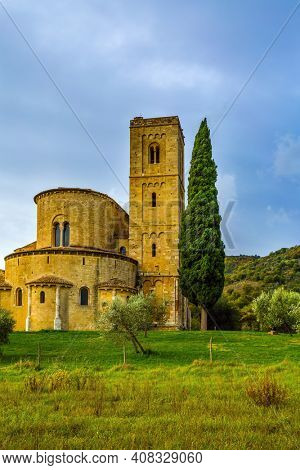 Picturesque Tuscany. Ancient medieval magnificent abbey of San Antimo. Autumn day. Tall slender cypress adorns the facade of the abbey.  The concept of active, rural and photo tourism