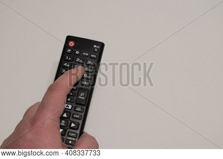 Hand Holding Black Multimedia Tv Remote Control On Yellow Background.pushing Button To Change Tv Cha