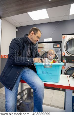 Prague, Czech Republic - 16.12.2020: Man With His Baby Waiting For Laundry In Laundry Room With Spee