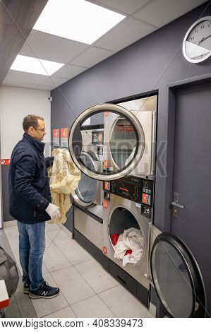 Prague, Czech Republic - 16.12.2020: Man Loading Washing Machine For Laundry In Laundry Room With Sp