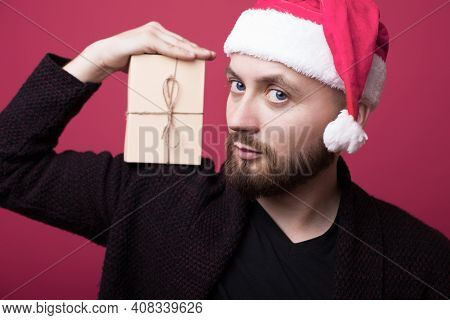 Close Up Photo Of A Bearded Man With Santa Hat Holding On Shoulder A Present And Smile At Camera On 