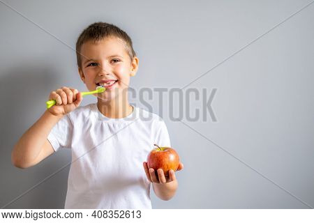 Boy Without Milk Upper Tooth In White T-shirt Smiling And Holding An Apple And Toothbrush In Hands O