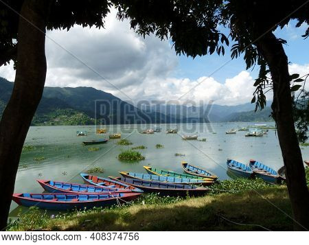 Colourful Bright Blue Rowing Boats On Tranquil Phewa Lake, Pokhara, Nepal With Clouds Reflected In W