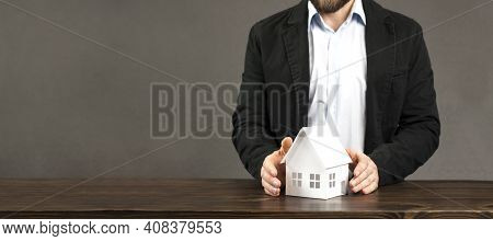 Miniature Layout Of A House In The Hands Of A Male Businessman. On The Table. Concept For Building O