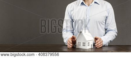Miniature Layout Of A House In The Hands Of A Male Businessman. On The Table. Concept For Building O