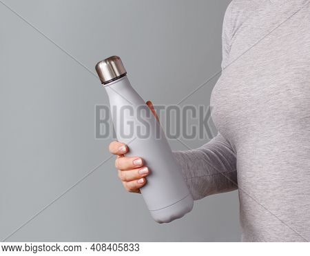 Close Up Of Woman In Grey Tee Holding Grey Insulated Bottle On Grey Background