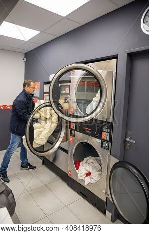 Prague, Czech Republic - 16.12.2020: Man Loading Washing Machine For Laundry In Laundry Room With Sp
