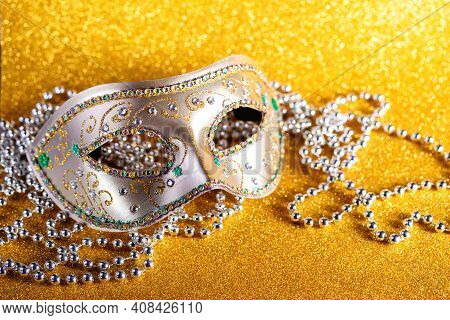 Festive, Colorful Mardi Gras Or Carnivale Mask And Beads On Golden Background. Venetian Masks. Party