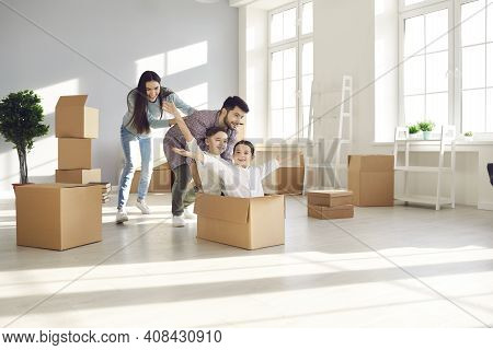 Happy Family Having Fun And Playing With Cardboard Boxes In Their Newly Bought House