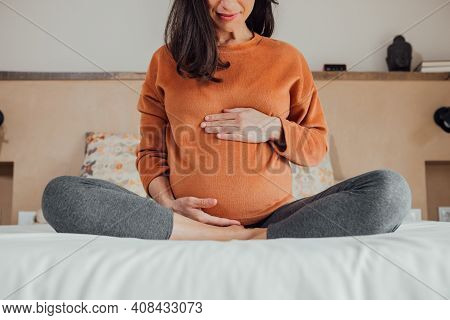 Front View Of Cropped Long Hair Brunet Caucasian Pregnant Woman, Sitting In Crossed Legs, In Yoga Po