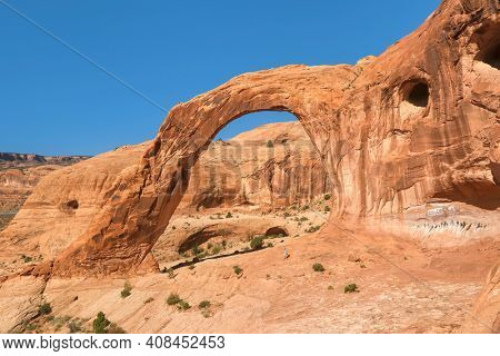 Corona Arch hiker heads under the arch during a three mile round trip hike along the sandstone slickrock near Arches and Canyonlands National Park, Utah. 