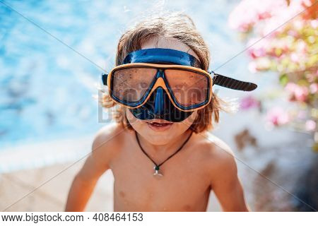 Swimming And Enjoynment. Cheerful Kid With Naked Body Weared With Goggles Looks At Camera In Backgro