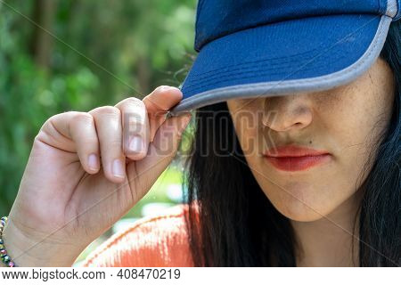 Woman Hiding Her Face Behind A Blue Basecap