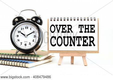 Otc - Over The Counter. Text On White Notepad Paper On A Stand Next To Our Desk Clock On A Sideboard