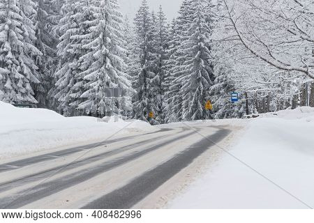 Jizera Mountains In Poland. Asphalt Road Covered With Broken Snow. Black Ruts. It Is The Provincial 