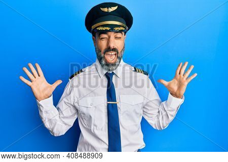 Middle age man with beard and grey hair wearing airplane pilot uniform celebrating mad and crazy for success with arms raised and closed eyes screaming excited. winner concept 