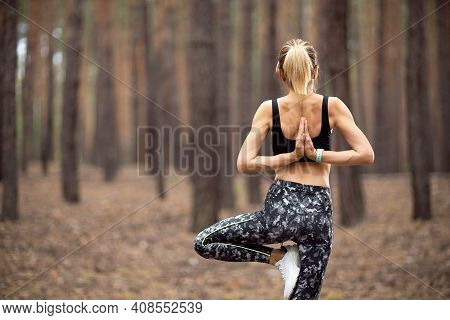 Beautiful Woman Standing And Doing Yoga In Forest. Exercise And Meditation Concept. Pay Obeisance Or