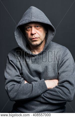 Studio Portrait Of A 40-50-year-old Serious Man In A Gray Hoodie On A Neutral Background, Eyes Direc