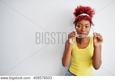 African American Woman In Yellow Singlet And Eyglasses Against White Wall.
