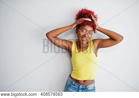 African American Woman In Yellow Singlet And Eyglasses Against White Wall.