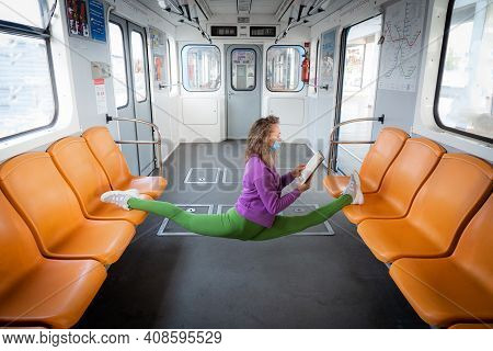 Flexible Female Yogi Wearing Mask Reading Book In The Underground Carriage Sitting In Gymnastic Spli