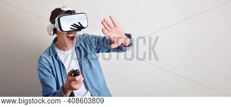 Modern Adult Man Interacting With Virtual Reality Glasses Controlling With A Joystic With Light Isol