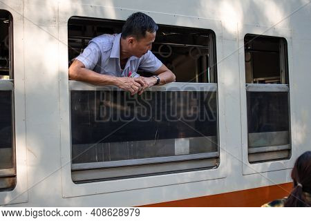 Yangon, Myanmar - Decemeber 31 2019: A Local Burmese Man Leans Out Of An Open Window When Standing S