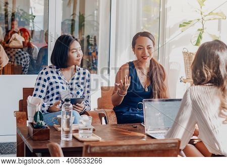 Female Team Of Asian Women Sit At Table Together And Planning Their Prohect Using A Laptop In Comfor