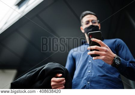 Middle Eastern Entrepreneur Wear Black Face Mask And Eyeglasses Look At Mobile Phone. New Normal Lif