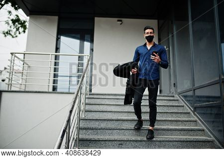 Middle Eastern Entrepreneur Wear Black Face Mask And Eyeglasses Look At Mobile Phone. New Normal Lif