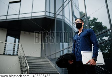 Middle Eastern Entrepreneur Wear Black Face Mask And Eyeglasses Hold Laptop. New Normal Life After C