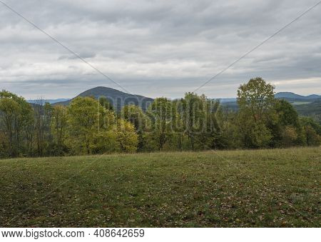 Meadow With Autumn Colorful Forest, Trees And Hills, Moody Sky. Landscape In Luzicke Hory Lusatian M