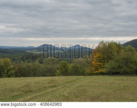 Meadow With Autumn Colorful Forest, Trees And Hills, Moody Sky. Landscape In Luzicke Hory Lusatian M