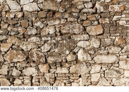 Old Stone Wall, Painted In A Faded White Color And Built With Stones And Mud