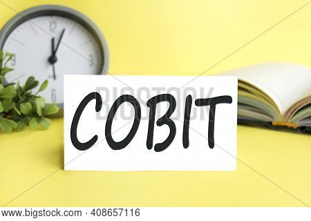 Cobit. Text On White Paper On A Yellow Background Near The Pen.