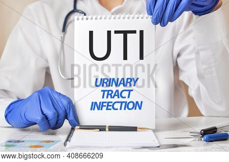 Uti Card In Hands Of Medical Doctor. Doctor's Hands In Blue Gloves Holding A Sheet Of Paper With Tex