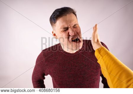 Crop Person Slapping Scared Man In Face. Emotional Male Getting Slapped In Face While Shouting With
