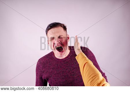 Crop Person Slapping Scared Man In Face. Emotional Male Getting Slapped In Face While Shouting With